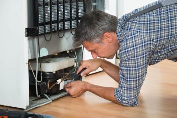 Technicien qualifié en train de réparer le système de refroidissement d'un réfrigérateur à l'arrière.