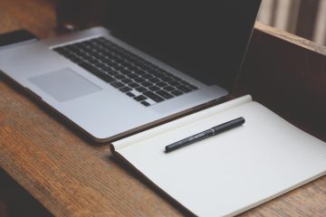 Laptop ouvert, cahier ligné et stylo noir sur table en bois