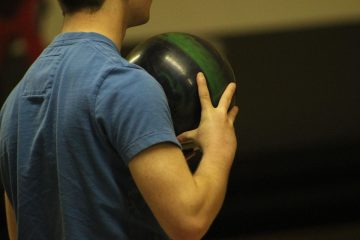 Un homme en t-shirt bleu tient une boule de bowling